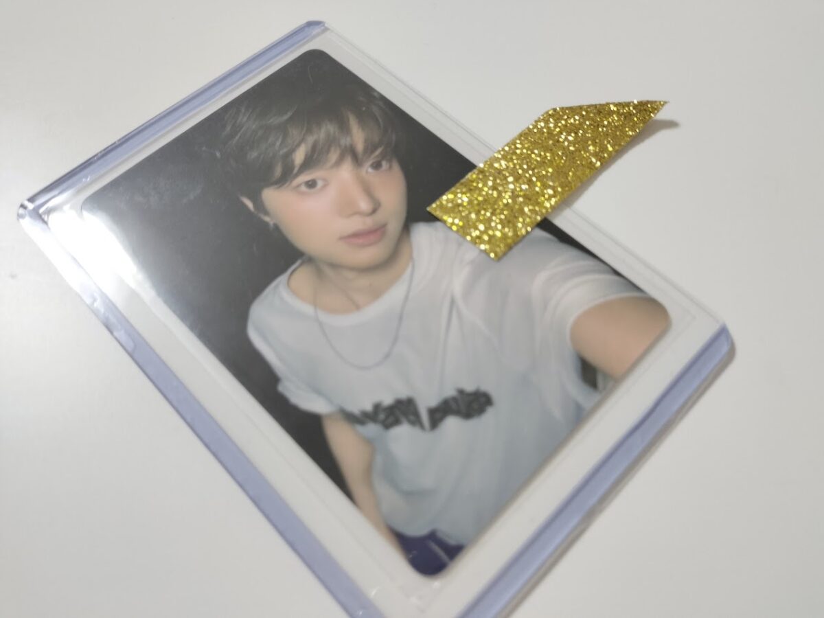 トレカを硬質ケースに入れ、上部をマスキングテープで封をした状態。&TEAM EJのトレカ